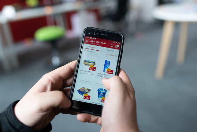 A person using the REWE app on a smartphone to order groceries online | © REWE digital, SEVN