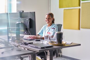 Lachende IT-Mitarbeiterin arbeitet an ihrem Schreibtisch