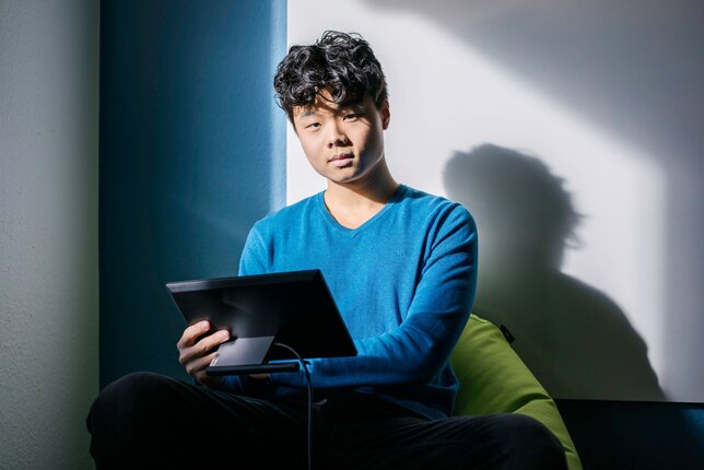 Symbolic image for comprehensive company care: a young man sitting on a bean bag working with a tablet | © REWE digital, Paula Winkler & Alexander Gehring