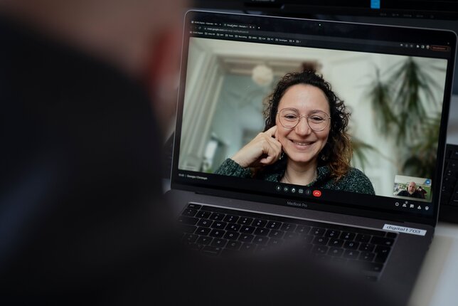 Eine Frau lächelt während einer Coaching-Sitzung per Videoanruf. | © REWE digital, SEVN